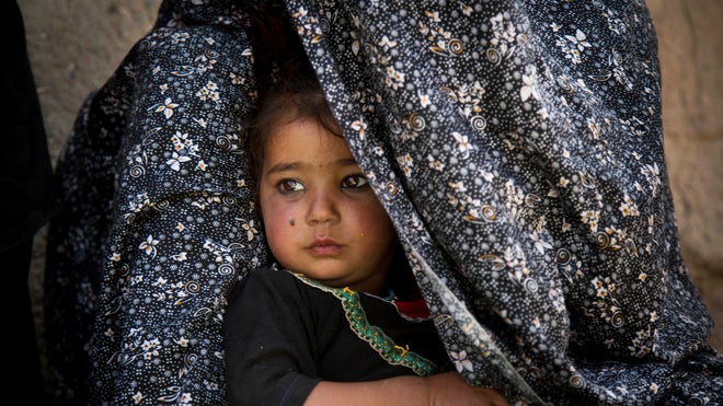 Sitting on a dirty straw mat on the parched ground of southern Afghanistan, Masooma sank deeper inside a giant black shawl.